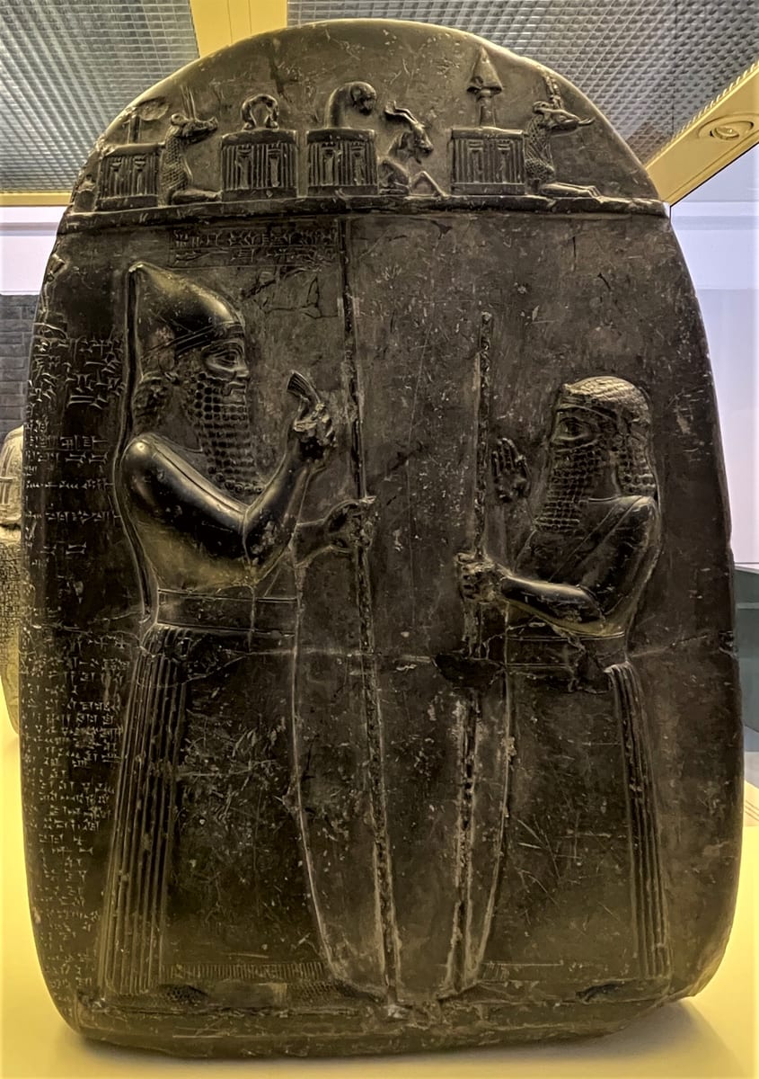 Marco de pedra negra com dois homens em pé, o rei e um oficial, e símbolos divinos no alto