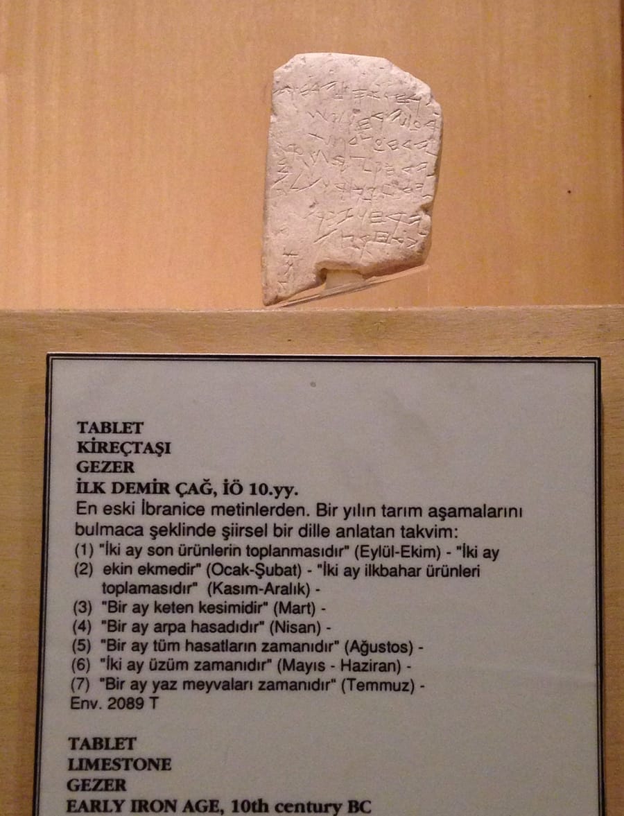 Pequena placa de calcário com sinais gravados, em uma vitrine, com a legenda do museu logo abaixo
