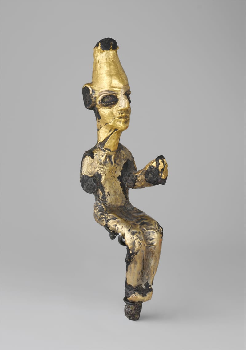Pequena estátua de bronze coberta de folha de ouro de um deus sentado, com coroa alta