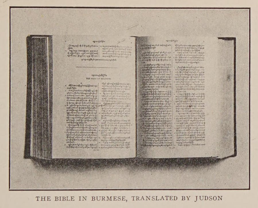 Fotografia de um grande volume aberto, com texto em escrita birmanesa em duas colunas e, na página da esquerda, o título em inglês The Song of Solomon; abaixo, a legenda The Bible in Burmese, translated by Judson