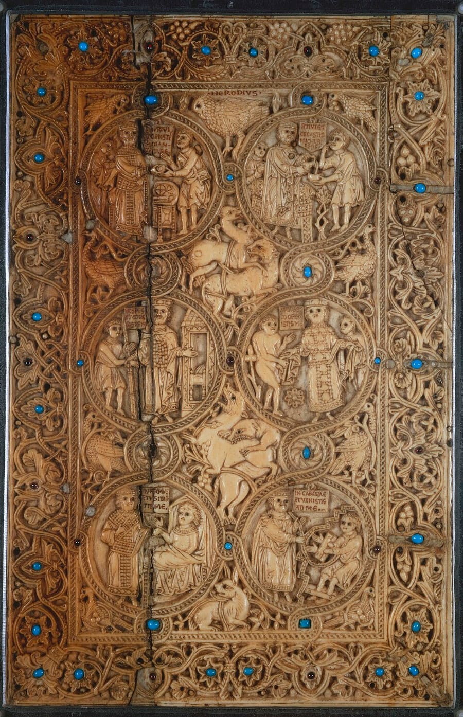 Capa de marfim talhado com turquesas, com seis medalhões circulares, cada um mostrando uma figura que socorre outra, entre folhagens, aves e animais