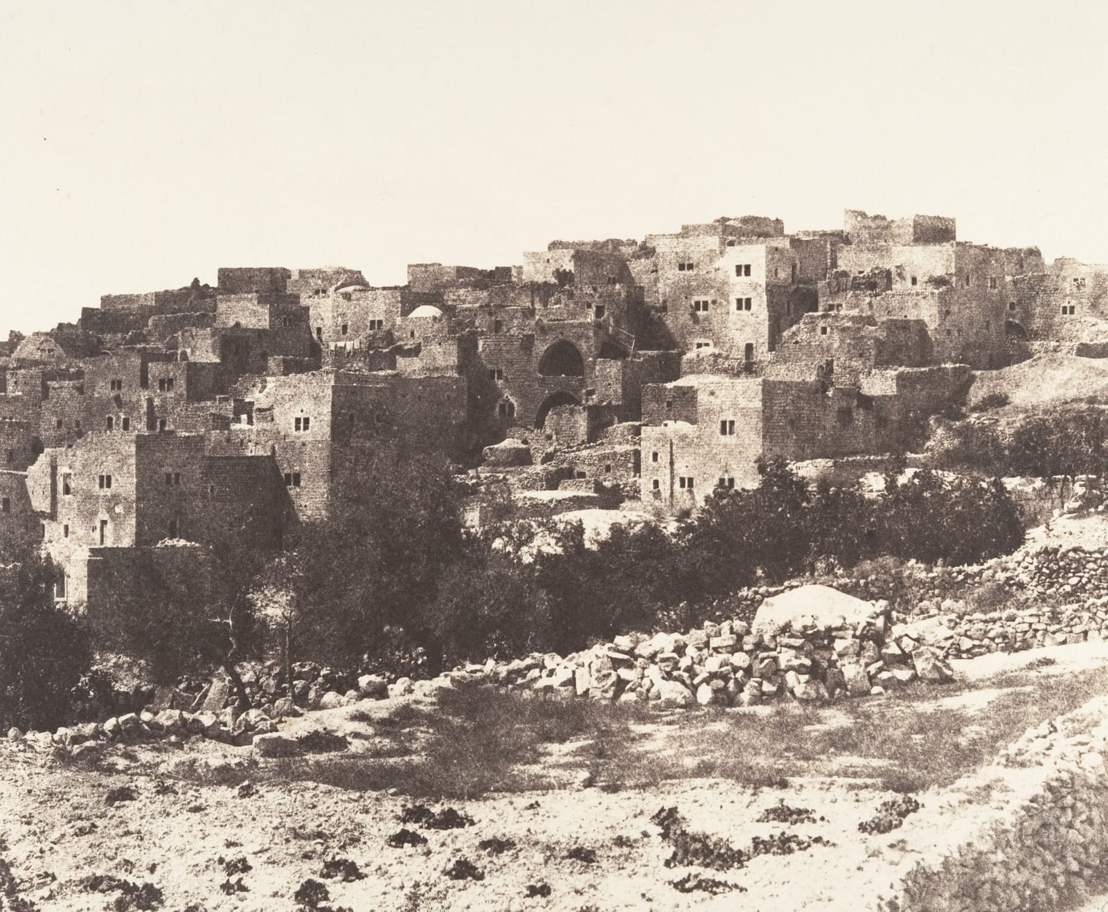 Fotografia antiga de Belém, com casas de pedra em encosta e muros de pedra em primeiro plano